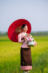 Pretty Asian women in traditional Thai dress. Beautiful traditional Thai dresses by Asian Buddhists make merit at the Temple a tourist attraction, a