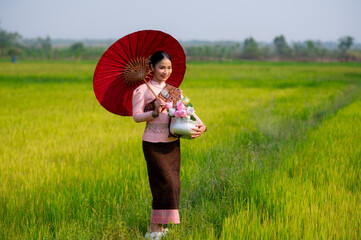 Pretty Asian women in traditional Thai dress. Beautiful traditional Thai dresses by Asian Buddhists make merit at the Temple a tourist attraction, a