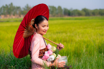 Pretty Asian women in traditional Thai dress. Beautiful traditional Thai dresses by Asian Buddhists make merit at the Temple a tourist attraction, a