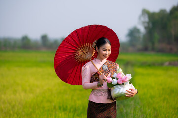 Pretty Asian women in traditional Thai dress. Beautiful traditional Thai dresses by Asian Buddhists make merit at the Temple a tourist attraction, a