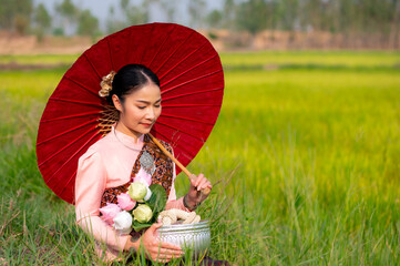 Pretty Asian women in traditional Thai dress. Beautiful traditional Thai dresses by Asian Buddhists make merit at the Temple a tourist attraction, a