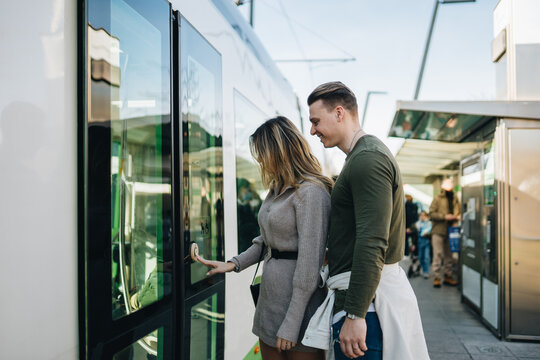 Young couple pushing button on train door on platform