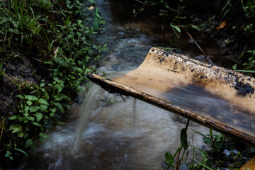 Water running over a tile forming a waterfall over a stream.