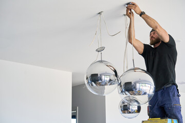 Electrician hanging large globe mirror lights