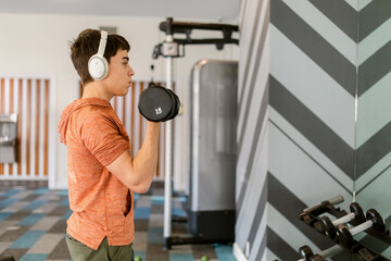 Teen boy lifts weight exercising at clubhouse