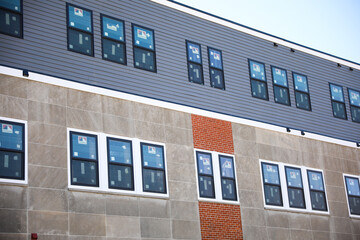 A sleek and modern building exterior with clean lines and large windows that reflect the blue sky. The building features a mix of concrete, steel, and glass, a futuristic and sophisticated look 