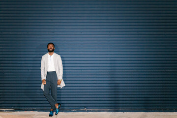 Black confident man standing against wall