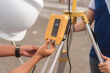 A surveyor setting up a wireless data transceiver. Surveying equipment used in the field. - obrazy, fototapety, plakaty