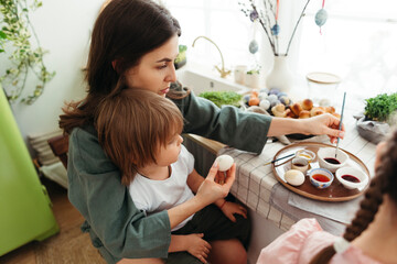 Mom with little son decorating Easter eggs.