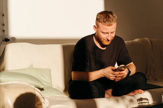 Stylish modern male using phone sitting at home.