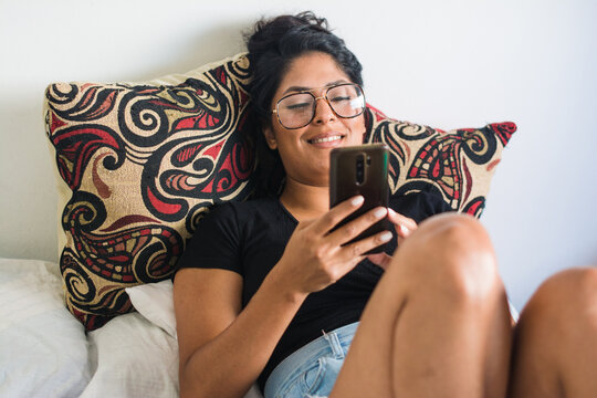 Happy woman texting in bed - Powered by Adobe