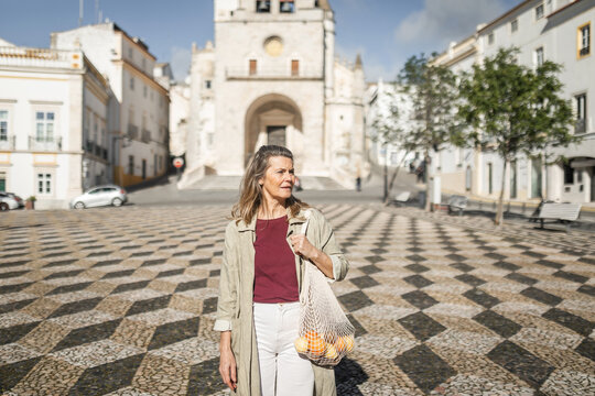 mature caucasian woman walking through a square in the city