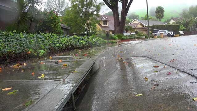 2023 - Excellent aerial footage of a storm drain catching rain waters outside a row of houses during a storm in Ventura, California.