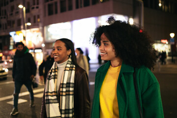 Young women crossing a city crosswalk at night