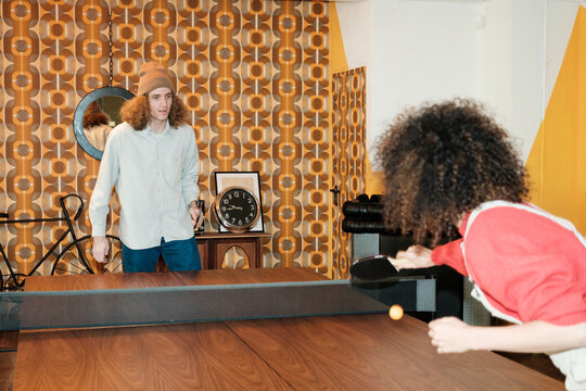 Work colleagues playing ping pong at modern office
