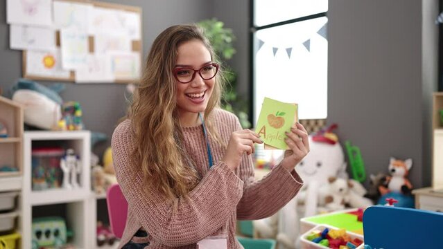 Young beautiful hispanic woman preschool teacher having vocabulary lesson at kindergarten