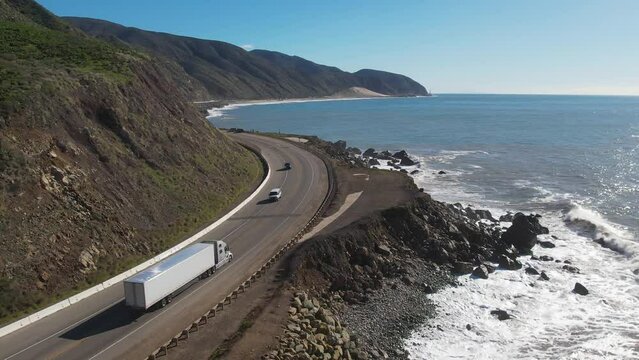 2023 - Excellent aerial footage of cars and trucks driving along the coast of Point Mugu, California as waves hit the shore.