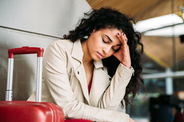 Upset woman sitting near luggage in airport