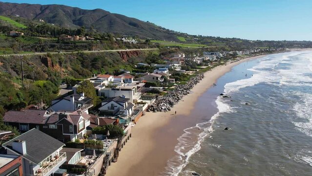 2023 - Excellent aerial footage pulling away from waves hitting the shore outside beach houses at Point Mugu, California.
