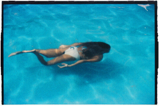 an anonymous girl dives in a swimming pool