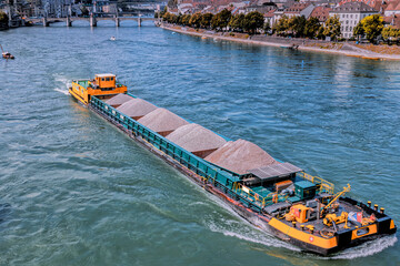 Self propelled barge carrying construction material in River Rhine, Basel, Switzerland