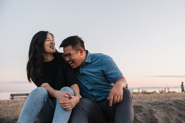 Relaxed romantic partners sitting outside on sand in the evening