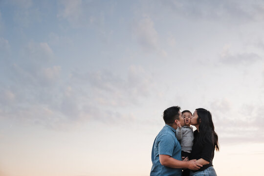 Family of three enjoying shoulder ride time together outside at 