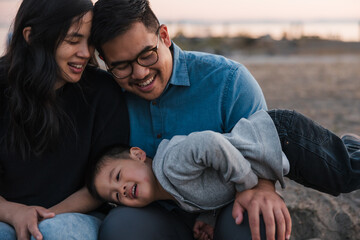 Family of three sitting and enjoying time together outside at su