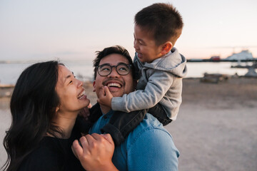 Family of three enjoying shoulder ride time together outside at 