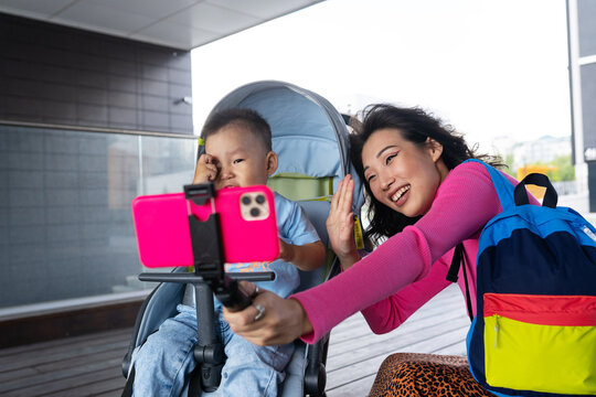 Asian mother taking selfie with baby on street
