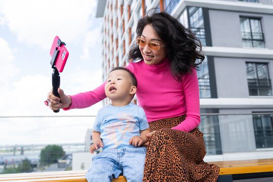 Asian mother taking selfie with baby on street