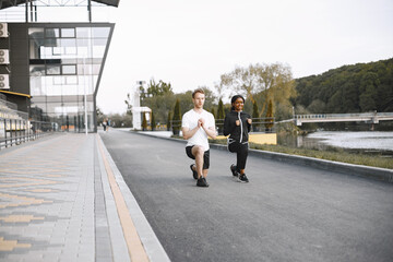 African-american woman and caucasian man training at the stadium