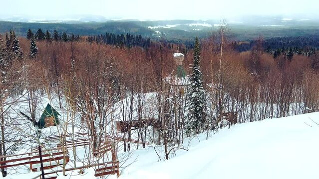 View of the chapel near the Belogorsky St. Nicholas Orthodox Missionary Monastery. Winter forest. The temple on the hill in winter. Russia, Perm Krai, Belaya Gora. 4K