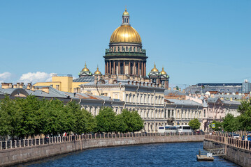 Fototapeta na wymiar The dome of St. Isaac's Cathedral over the Moika river on a sunny June day. Saint-Petersburg, Russia