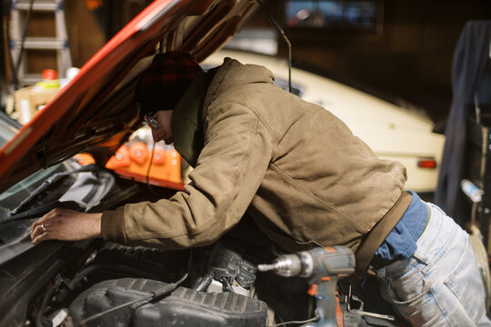 Millennial Mechanic working on a red car in workshop