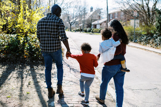Smiling multiracial family walking outdoors in neighborhood