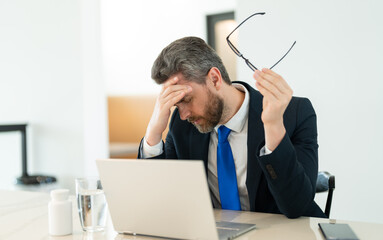 tired businessman has migraine in office. tired businessman has migraine while working.