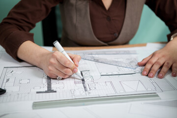 Architect working on blueprints on her desk. Working on new projects. Architecture and design