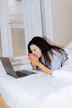 Woman Laughing With Face Mask Using Laptop in Bed