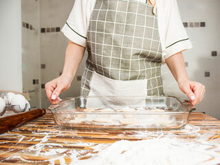 woman in an apron holds a glass baking sheet with cookies, close-up, housework