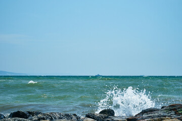Image of the sea shore. In the background is a warship.