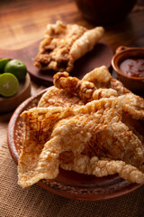 Chicharron. Crispy Fried pork rind, are pieces of aired and fried pork skin, traditional Mexican ingredient or snack served with lime juice and red hot sauce.