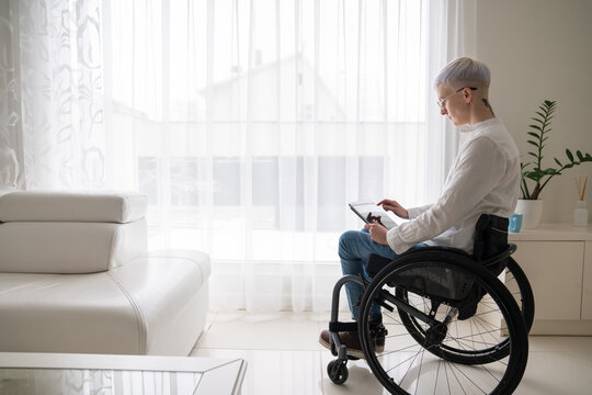 Woman In Wheelchair Using Tablet Indoors