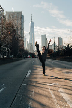 young woman performing in the street on a crossroad, leg swing