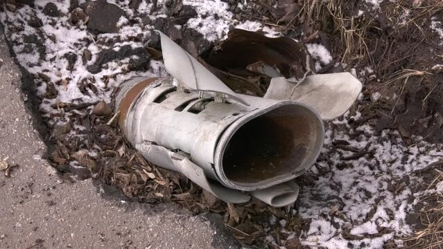 The remains of a rocket artillery shell stick out of the ground. Metal bar of artillery shell. Shelling of peaceful cities. Russian-Ukrainian War 2022-2023