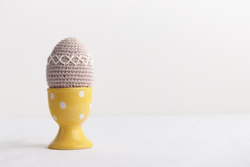 Easter crocheted egg in a yellow egg holder on white background