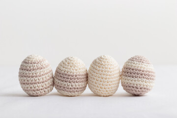 Row of cute striped pattern crocheted eggs, pastel color on a white