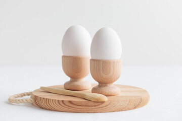 White eggs in a wooden egg holders standing on a white table