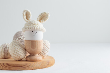 Easter egg in crochet hat with bunny ears in wooden egg holder