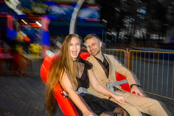 A frightened joyful couple in love rides at night on an attraction